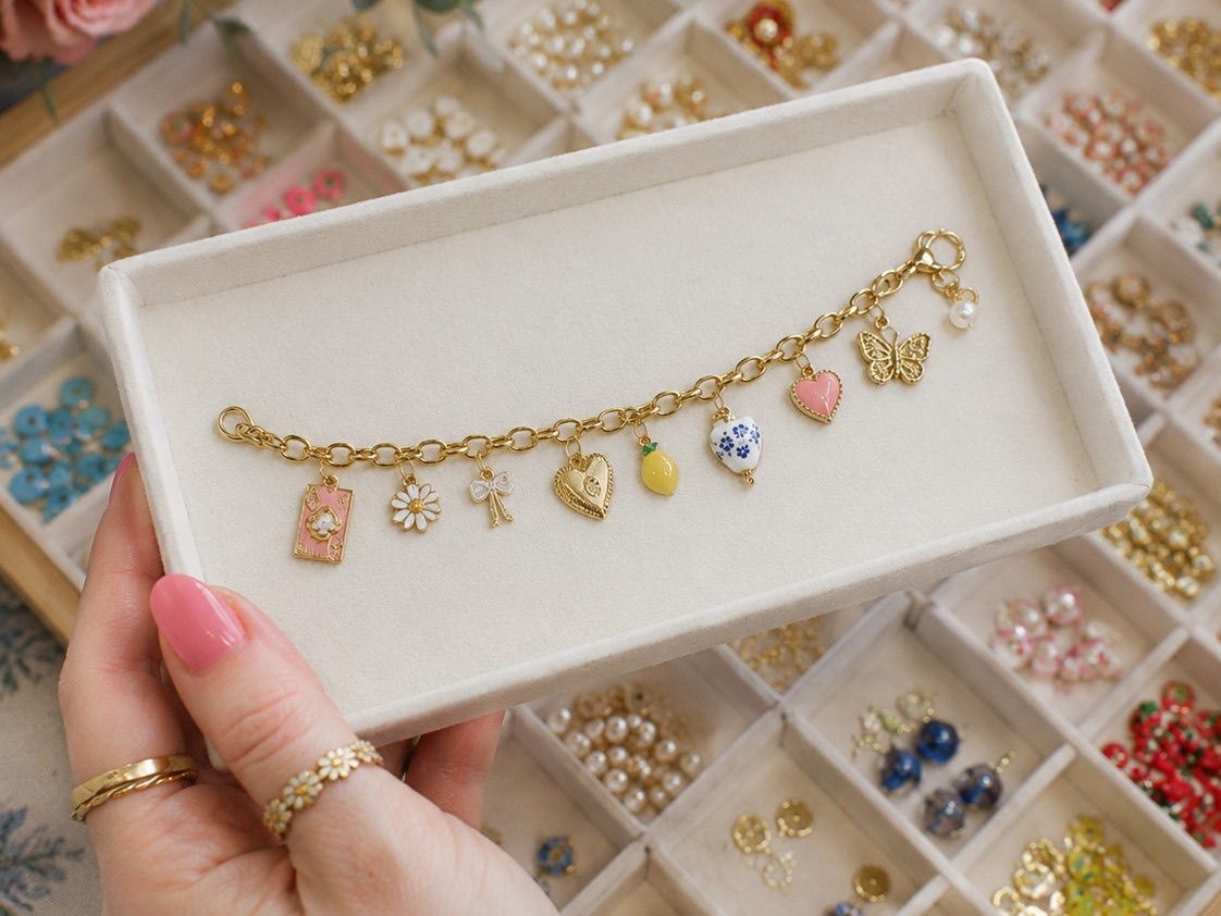Gold charm bracelet with enamel charms in a velvet tray