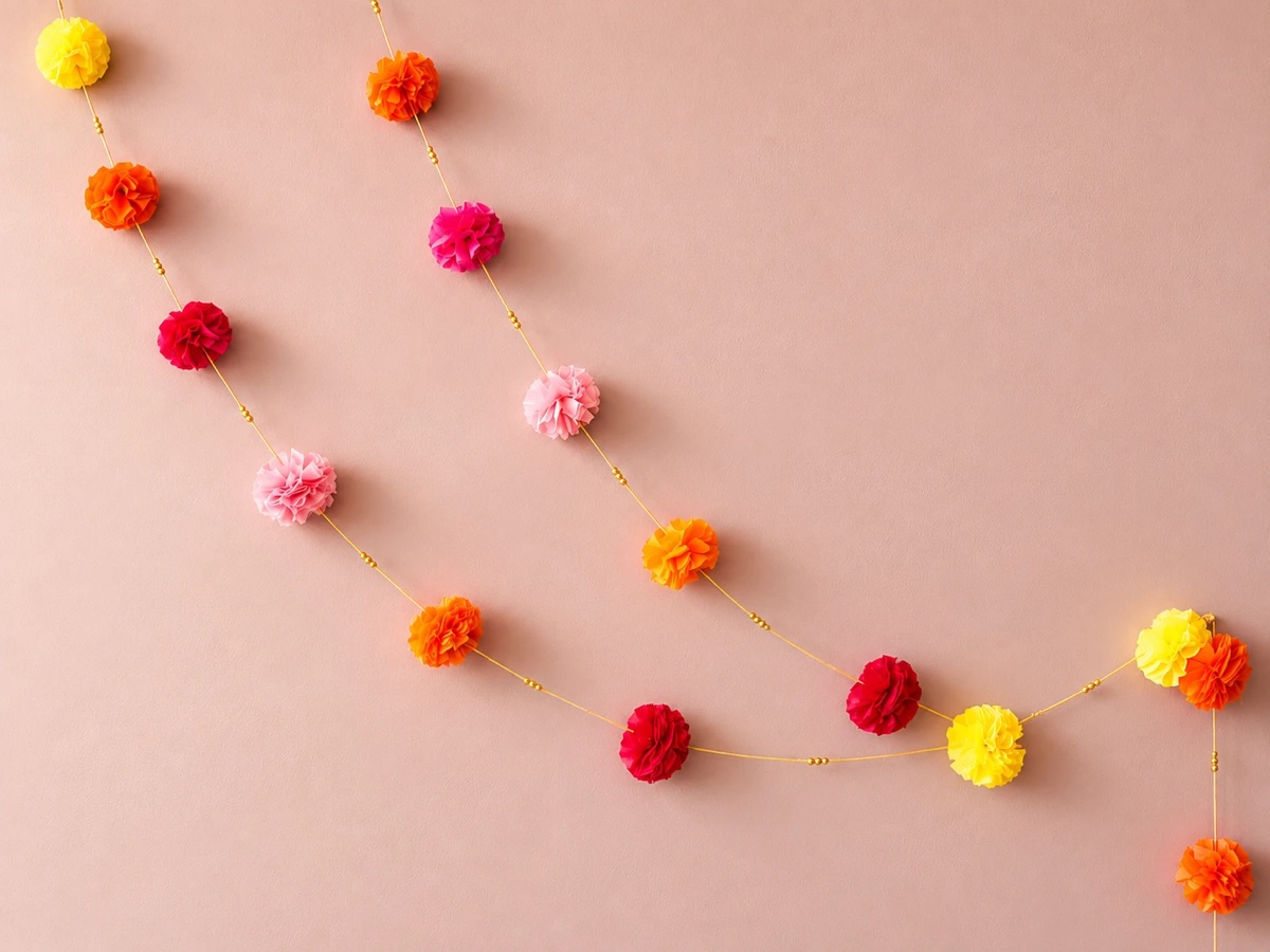 Two marigold garlands draped on a soft pink wall