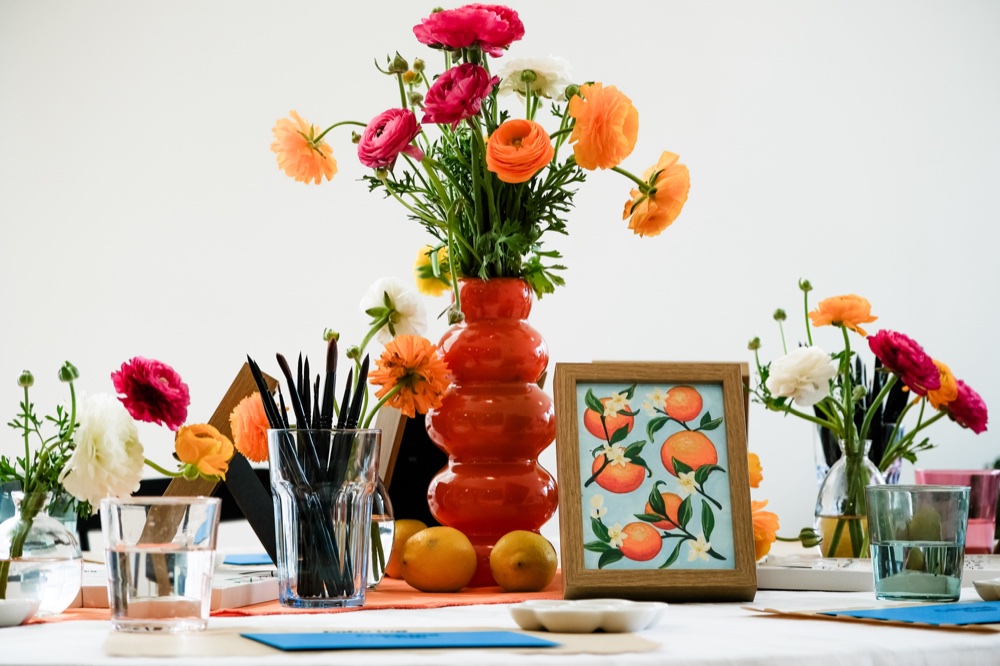 Sicilian Aperitivo, ranunculus in an orange vase with lemons and a painting of oranges